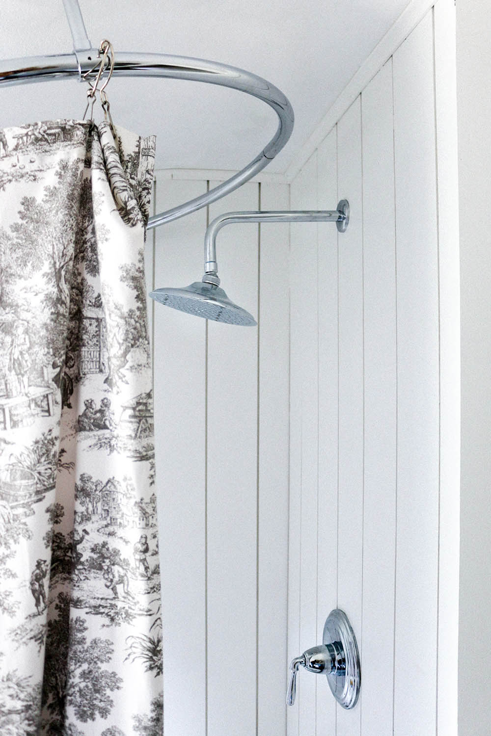 A chrome shower fixture installed on a white vertical shiplap wall.