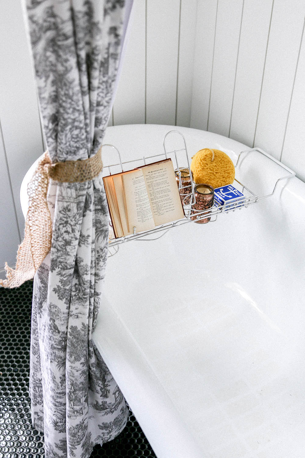 A shower curtain tied to the side of a clawfoot bathtub.