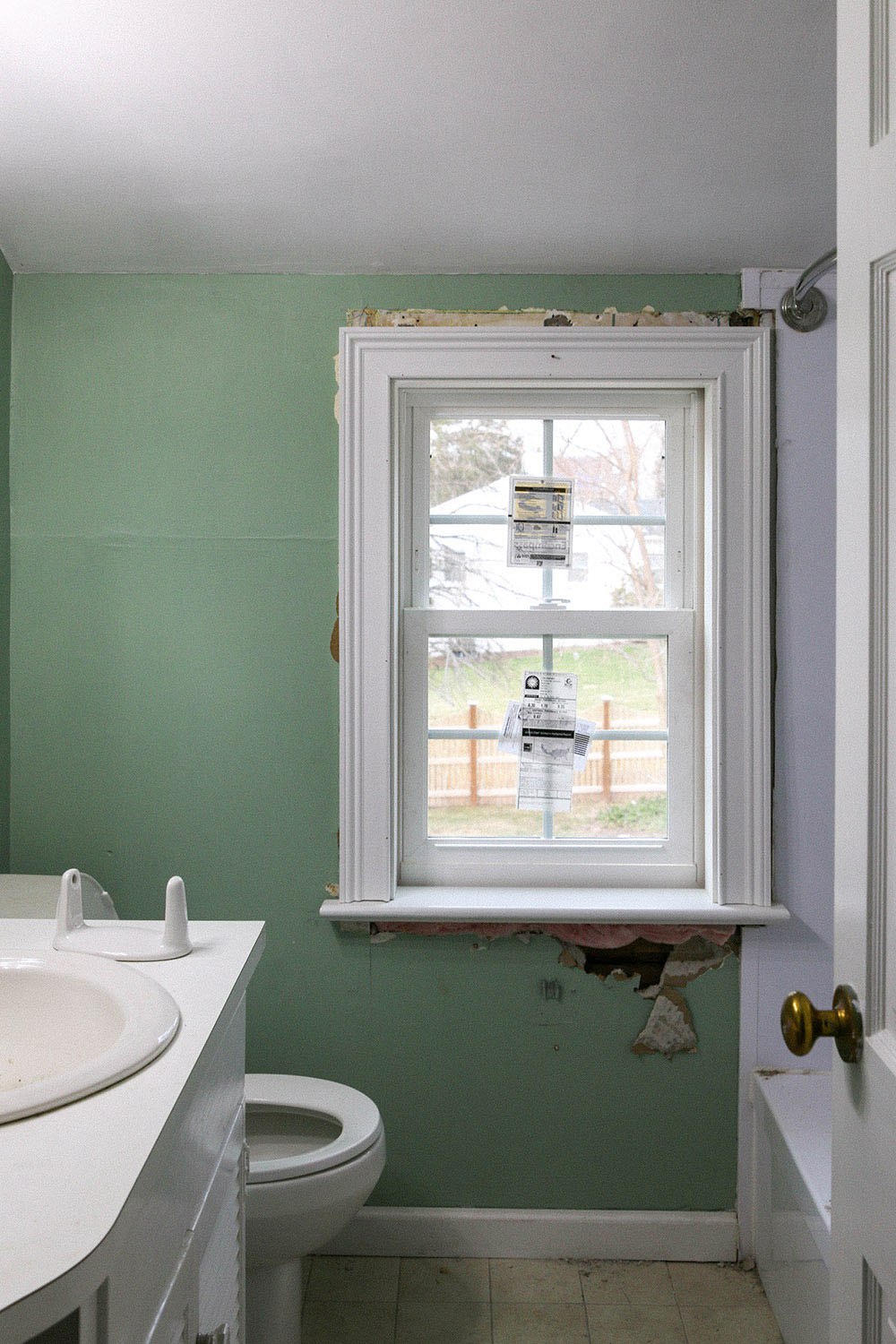 A bathroom with green walls and a new window.