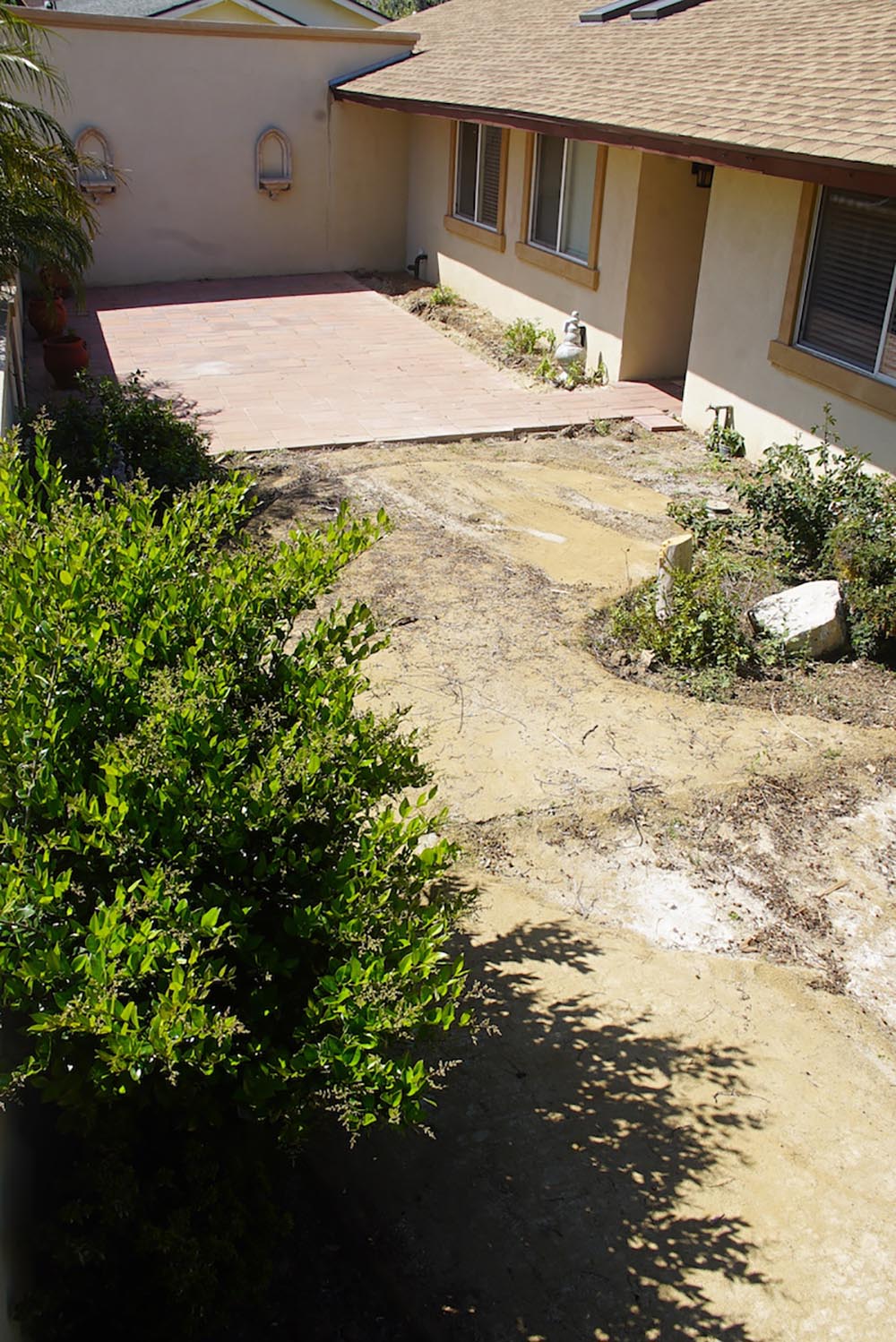 An empty courtyard with a patio and dirt that has not been landscaped.