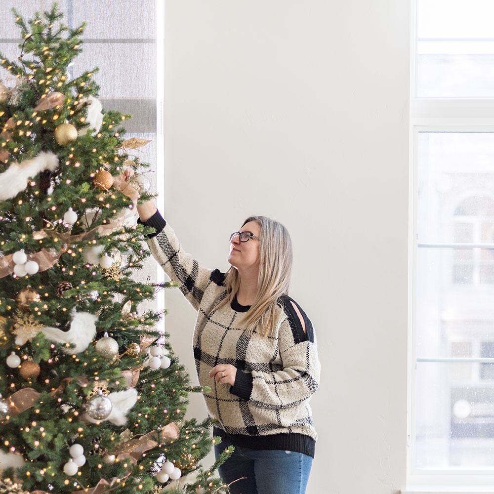 A woman decorates a Christmas tree.