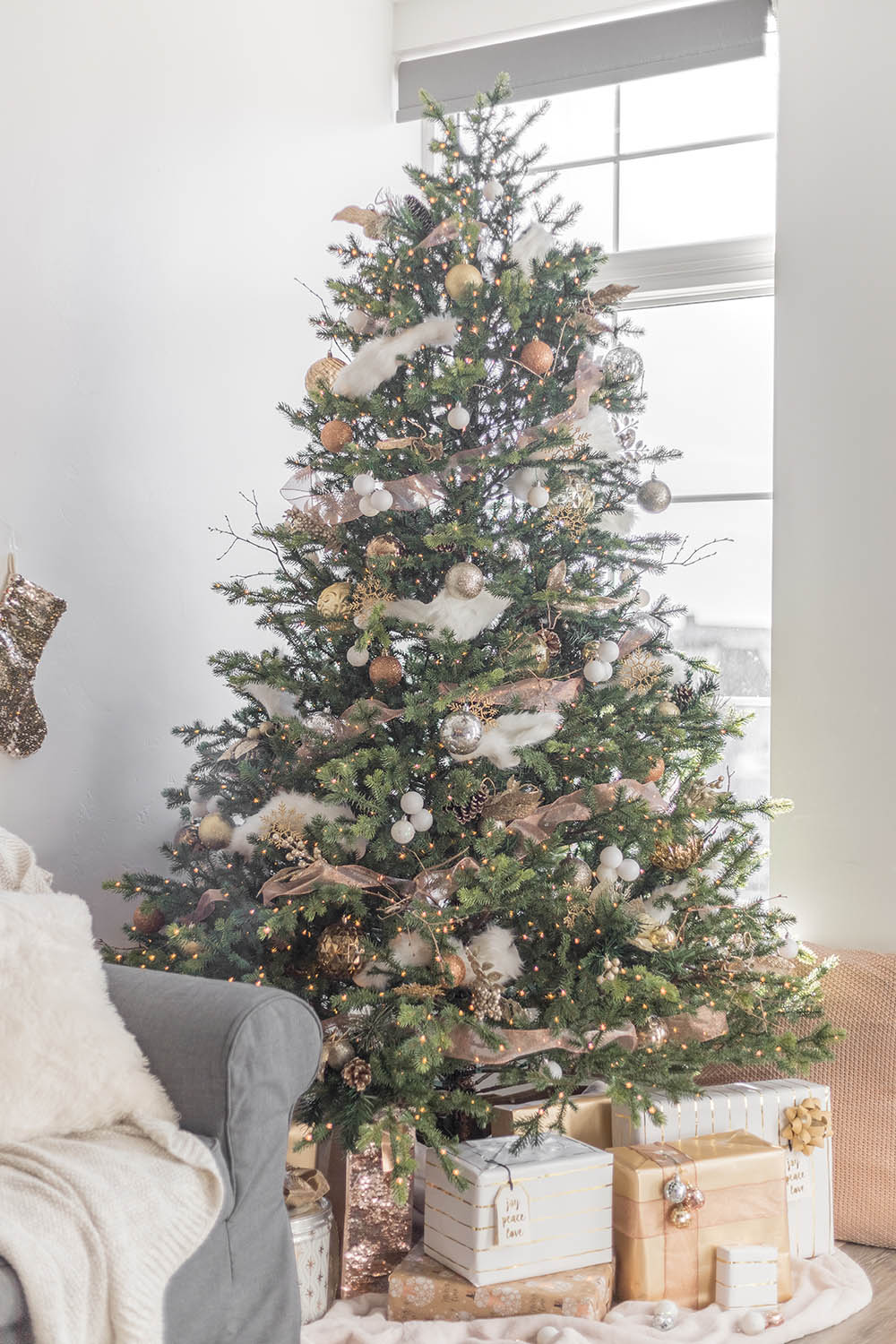 A Christmas tree decorated in white, gold, silver, and copper.