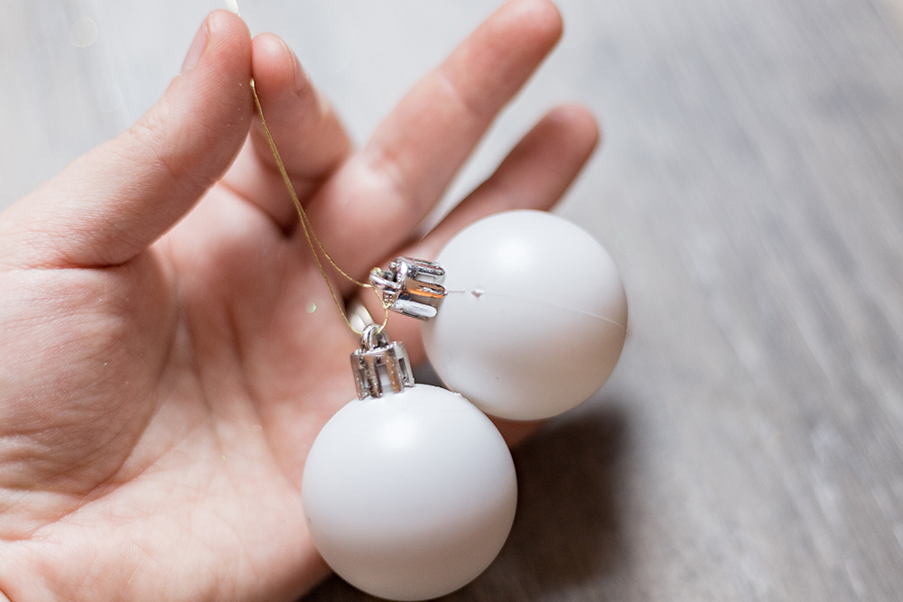 A person holding two small white ornaments together.
