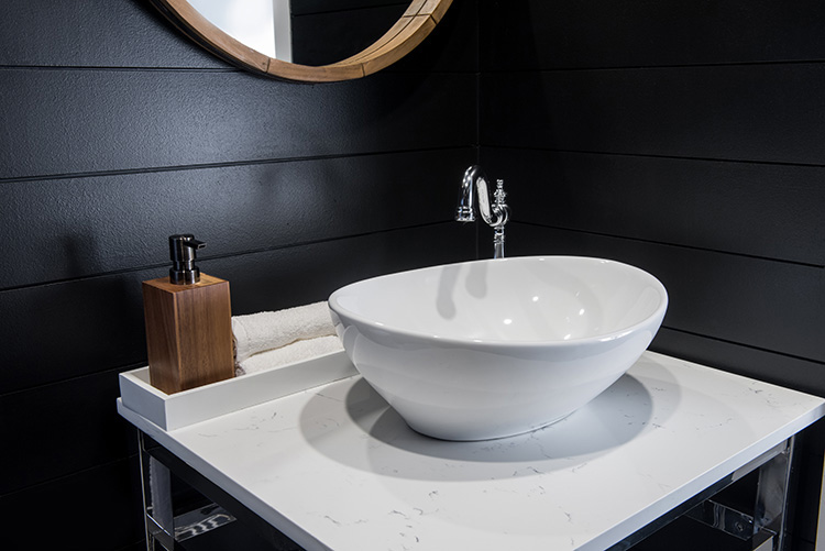 A white vessel sink stands out in front of a wall of black shiplap.