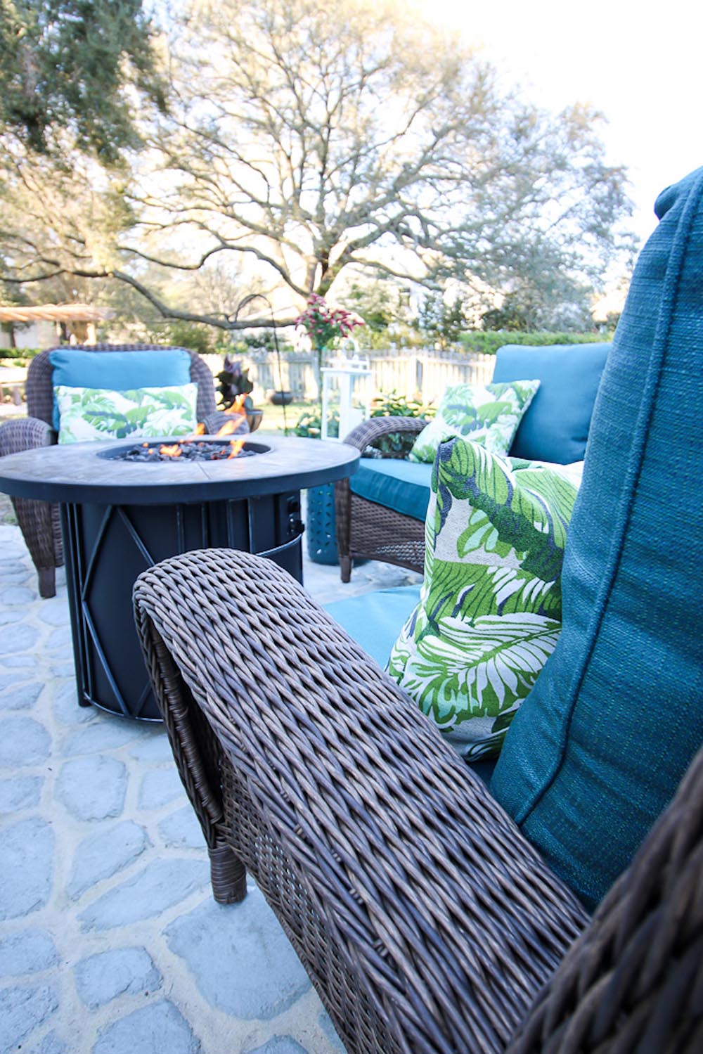 A burning fire pit sits in front of a wicker chair. A burning fire pit sits in front of a wicker chair.