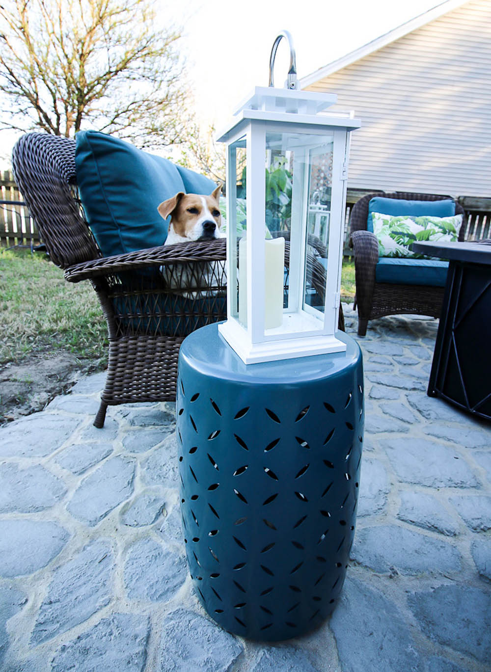 A white metal lantern sitting on a colored garden stool. A white metal lantern sitting on a colored garden stool.