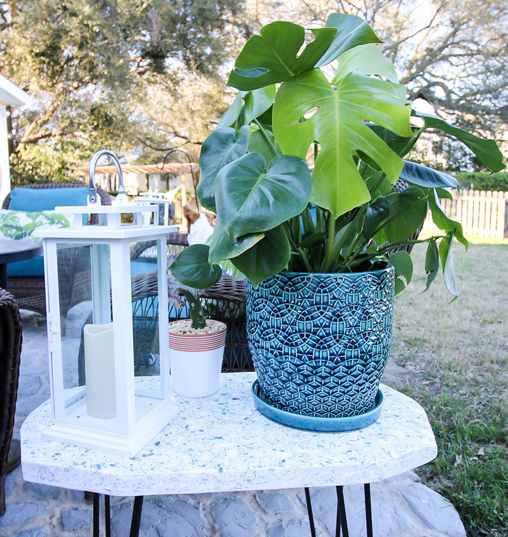 A plant potted in a bright colored planter sits on top of a DIY outdoor table. A plant potted in a bright colored planter sits on top of a DIY outdoor table.