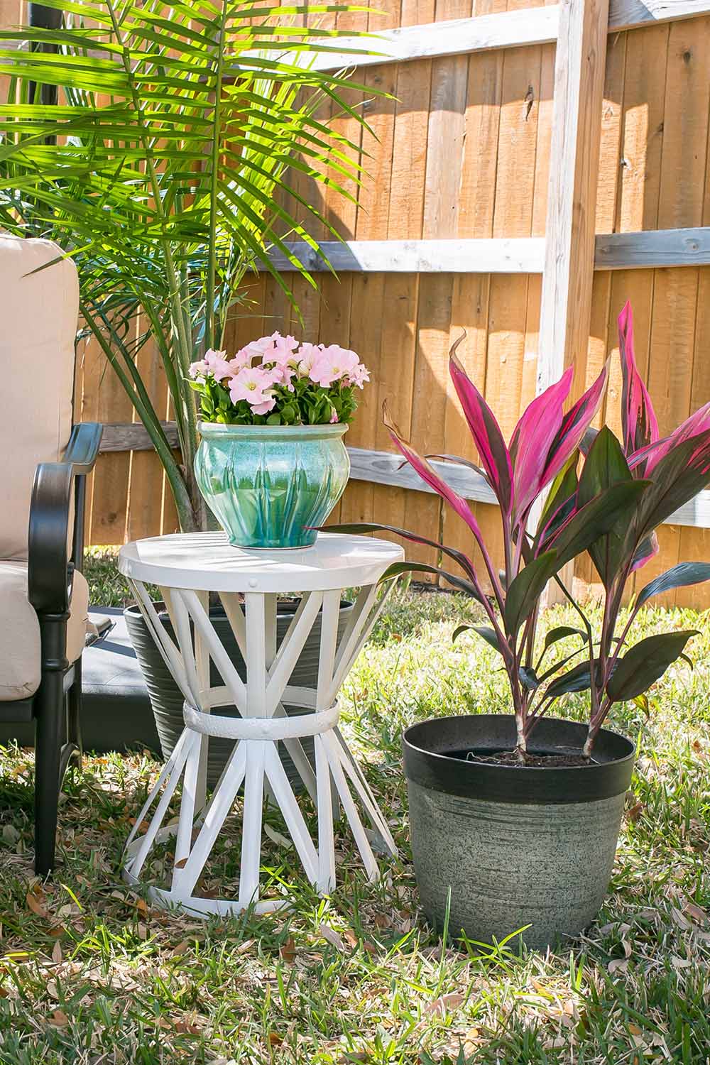 A Yucca plant in a planter next to a white garden stool. A Yucca plant in a planter next to a white garden stool.