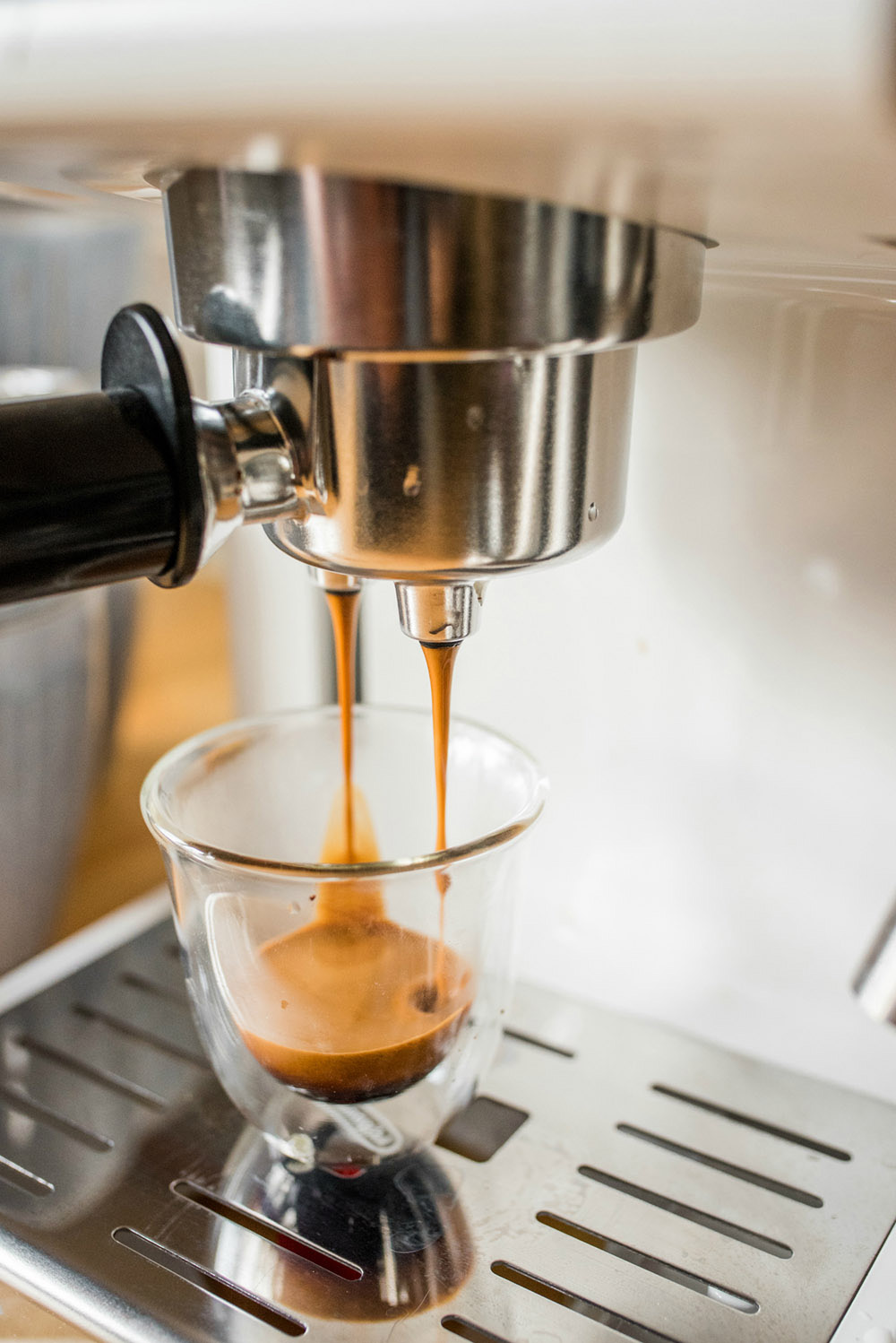 An espresso maker drips espresso into a cup.