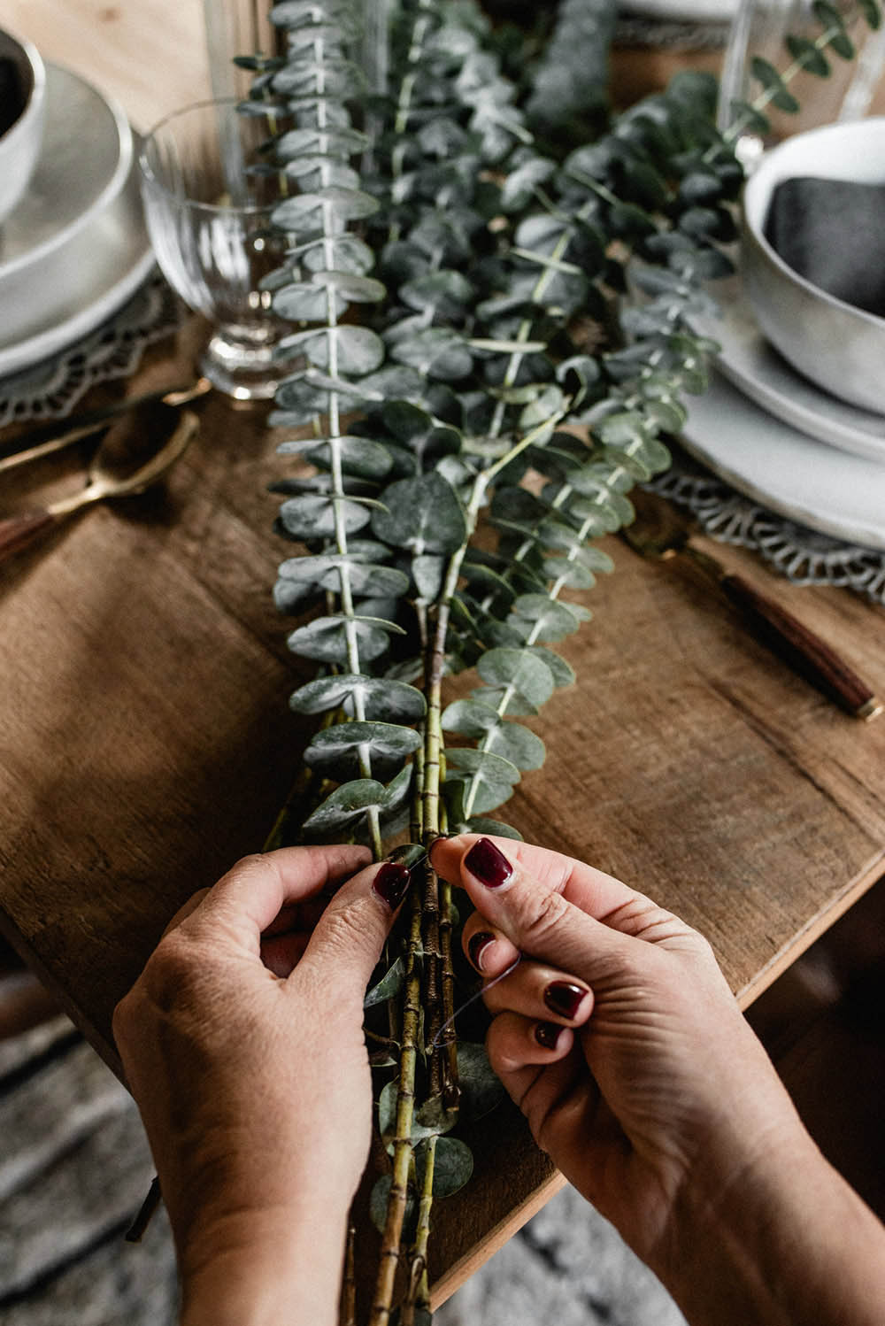 A person ties together the ends of a eucalyptus garland.