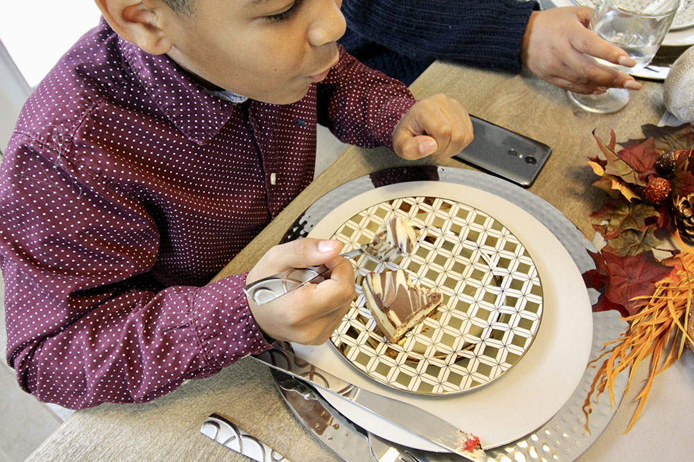A young boy eating dessert off a gold decorative dessert plate.