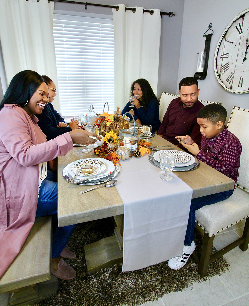 A group of people smiling around a table for Friendsgiving.