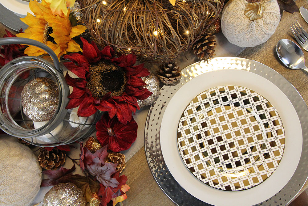 A place setting with a silver charger, white dinner plate, and gold decorative salad plate. A place setting with a silver charger, white dinner plate, and gold decorative salad plate.
