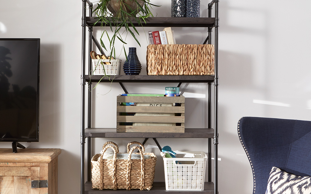 Baskets and crates stand on the shelves of a freestanding shelving unit. 