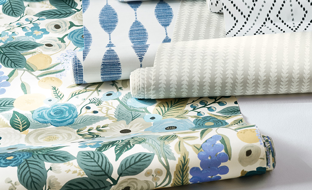Rolls of wallpaper in various designs and colors lay next to each other.