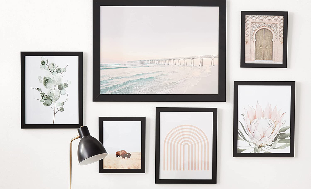 Six pieces of artwork in matching black frames hang in a grouping on the wall of an office.