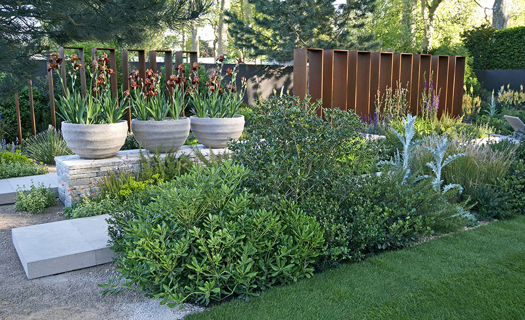 Planters with flowers next to shrubs in a landscape