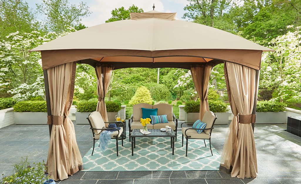 Outdoor curtains around an outdoor dining table and chairs.
