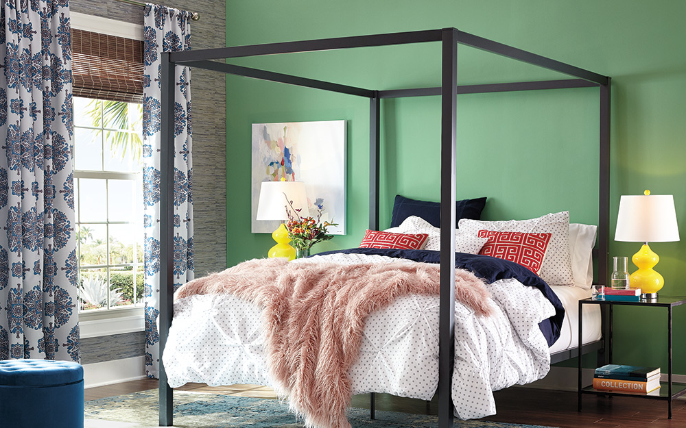 A bedroom with patterned curtains hanging over the window.