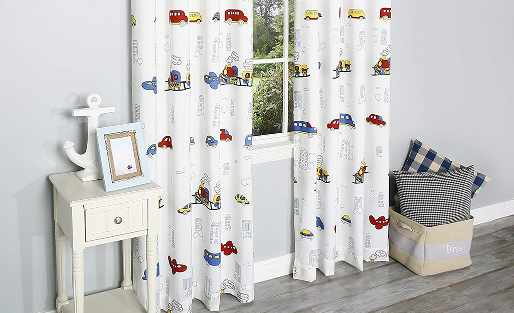 White curtains with multi-colored cars on them in a child's room.