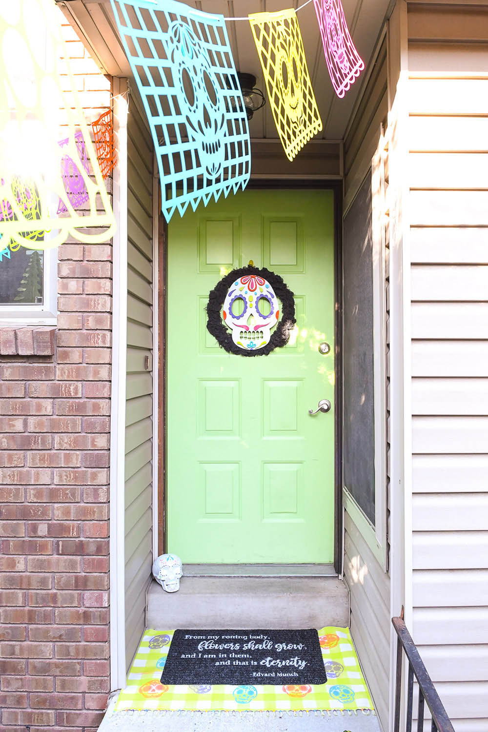 A sugar skull wreath hanging on a bright green front door.