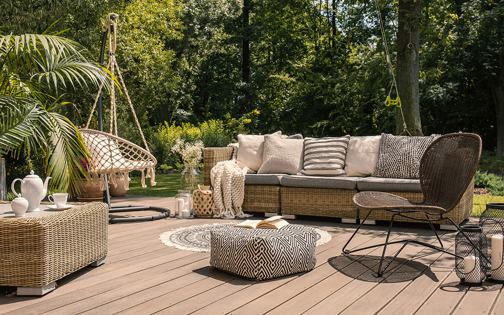 A freestanding deck includes such matching furnishings as an outdoor sofa, ottoman, hanging chair and a small rug.