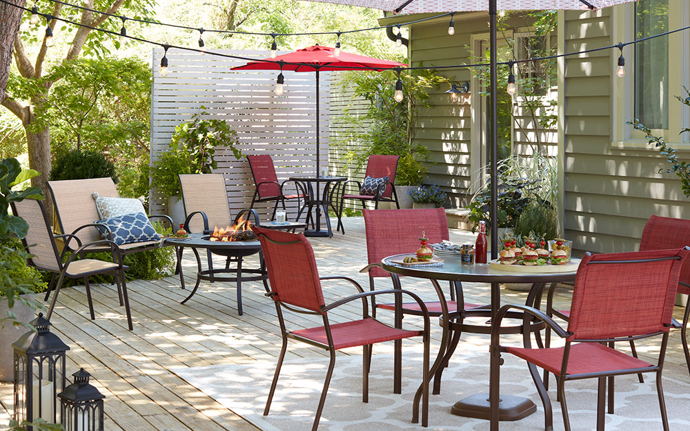 A backyard deck includes two sets of tables and chairs for outdoor dining.