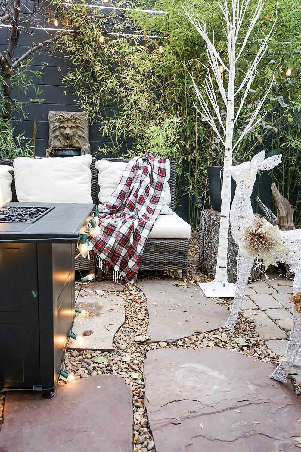 A small outdoor patio space decorated for the holidays with lights.