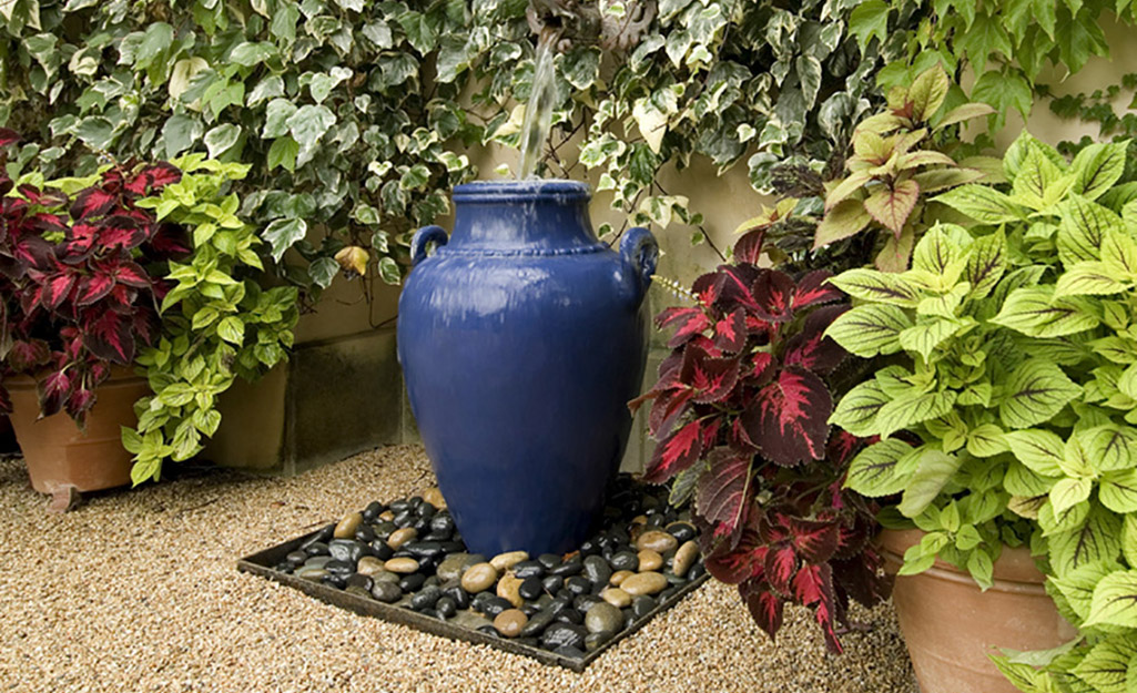 Decorative river rocks surrounding a blue garden urn on a bed of small stone gravel.