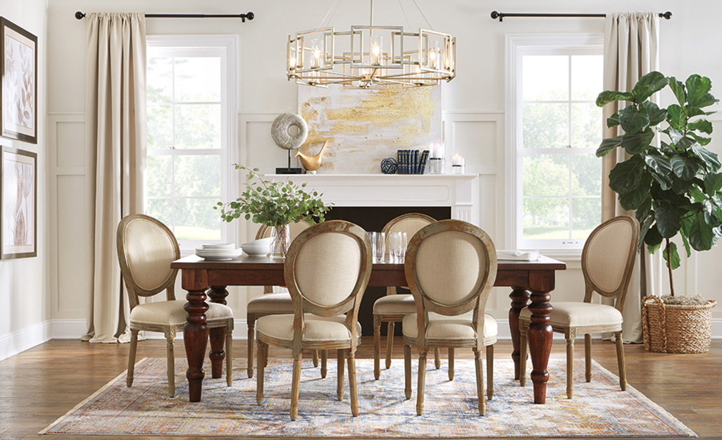 A luxury dining room with circle back dining chairs and a gold chandelier. 