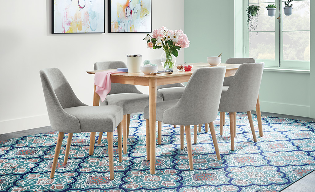 A vase and other finishing touches decorate a dining table with cushioned chairs.