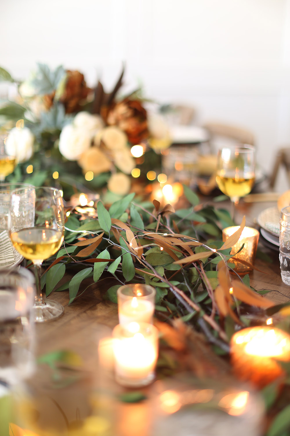 A tabletop decorated with Fall greenery and small candles. A tabletop decorated with Fall greenery and small candles.