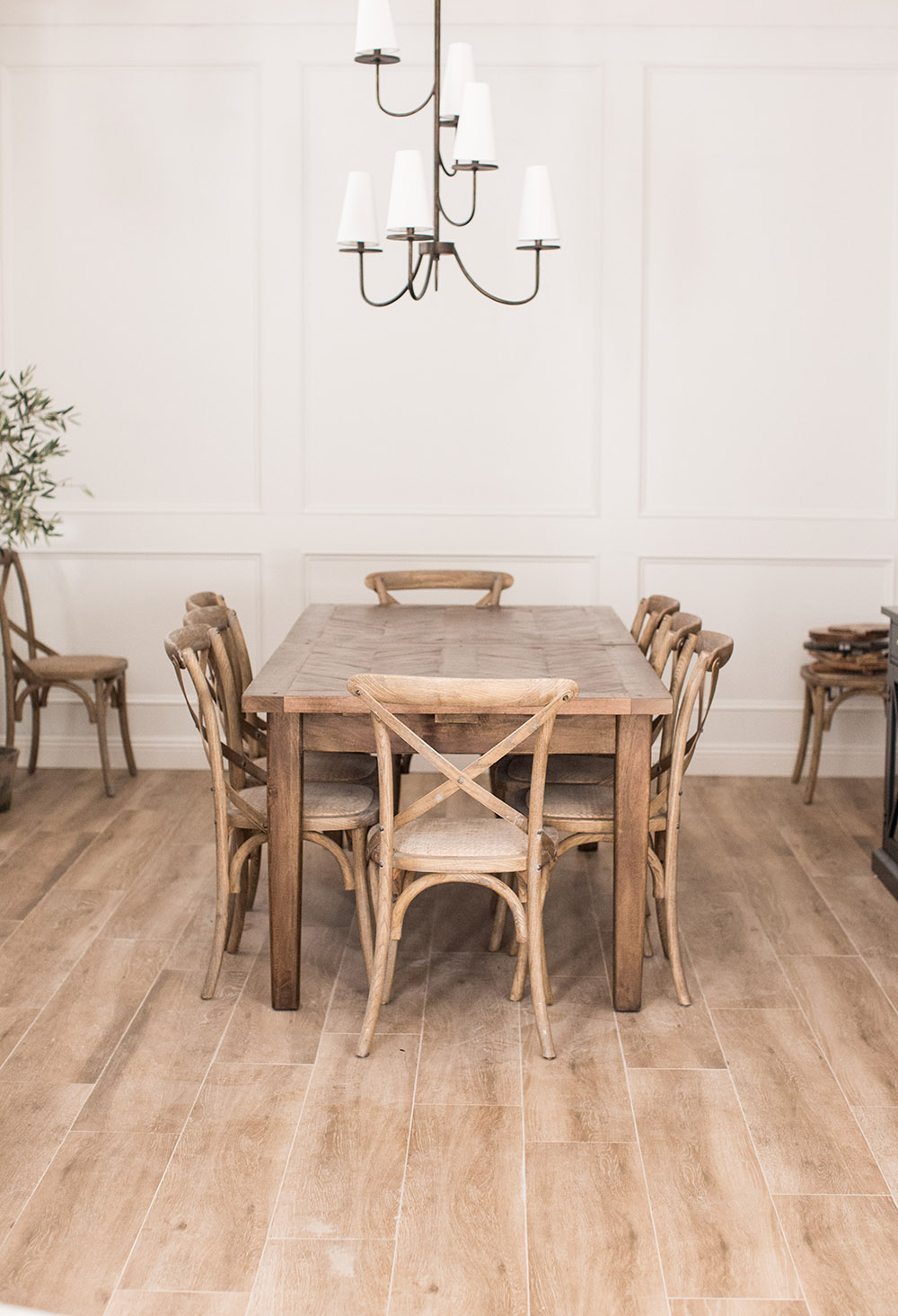 A large chandelier hangs over a wooden dining room table. A large chandelier hangs over a wooden dining room table.