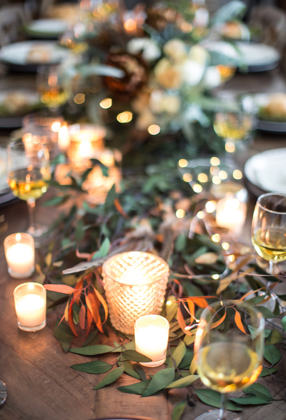 A dining table decorated with greenery and candles. A dining table decorated with greenery and candles.
