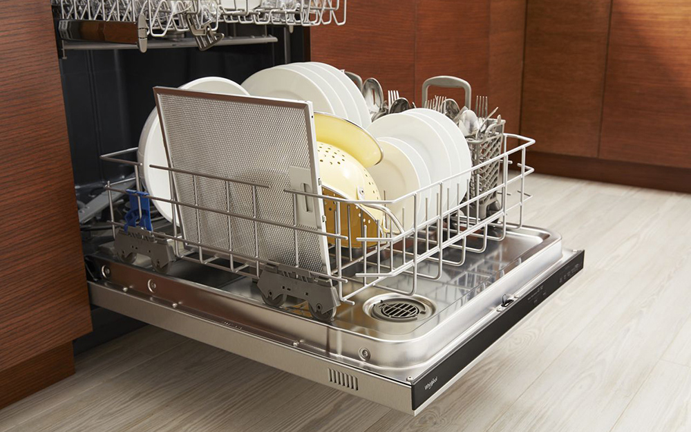 An open built-in dishwasher revealing a rack filled with dishes.