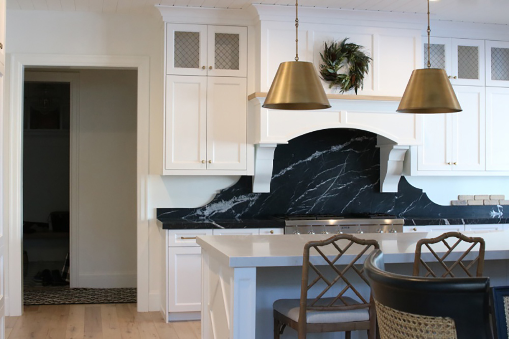 A kitchen with a black marble backsplash behind an oven.