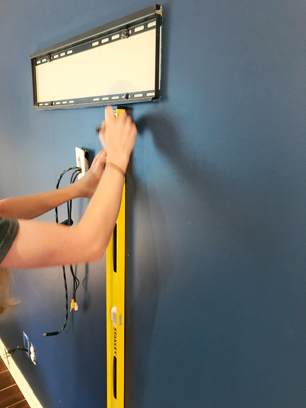 A person marks the center and studs on a wall. A person marks the center and studs on a wall.