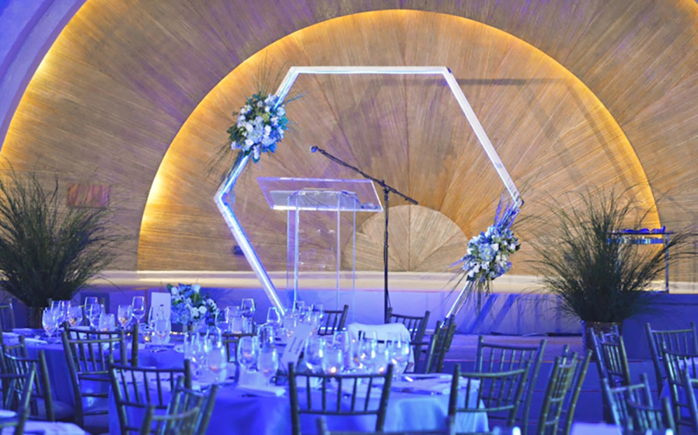 A hexagon shaped backdrop decorates a wedding reception.