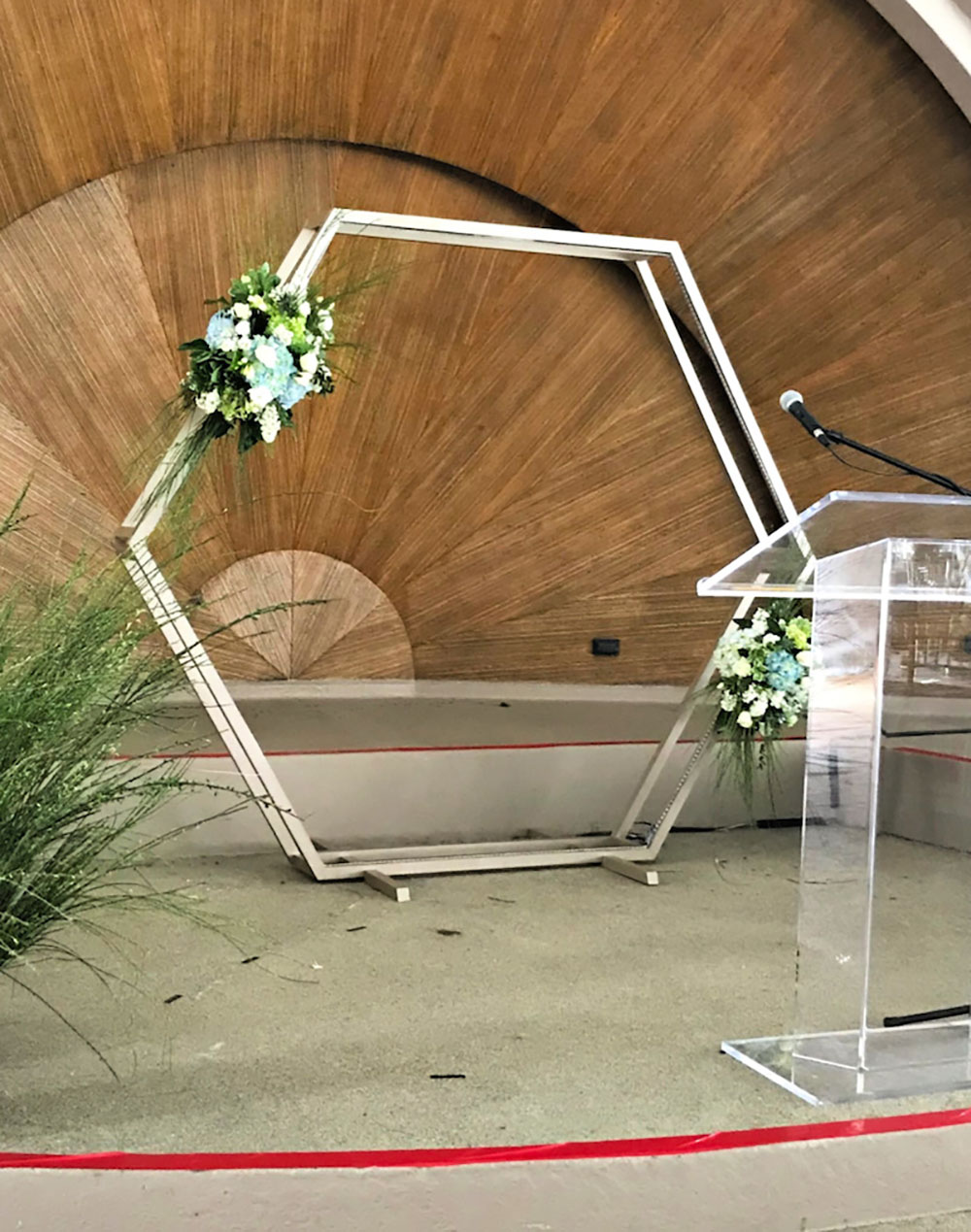 A clear podium stands in front of a DIY hexagon backdrop.
