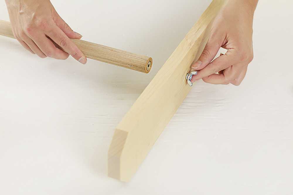 A person positioning a dowel into an upright.