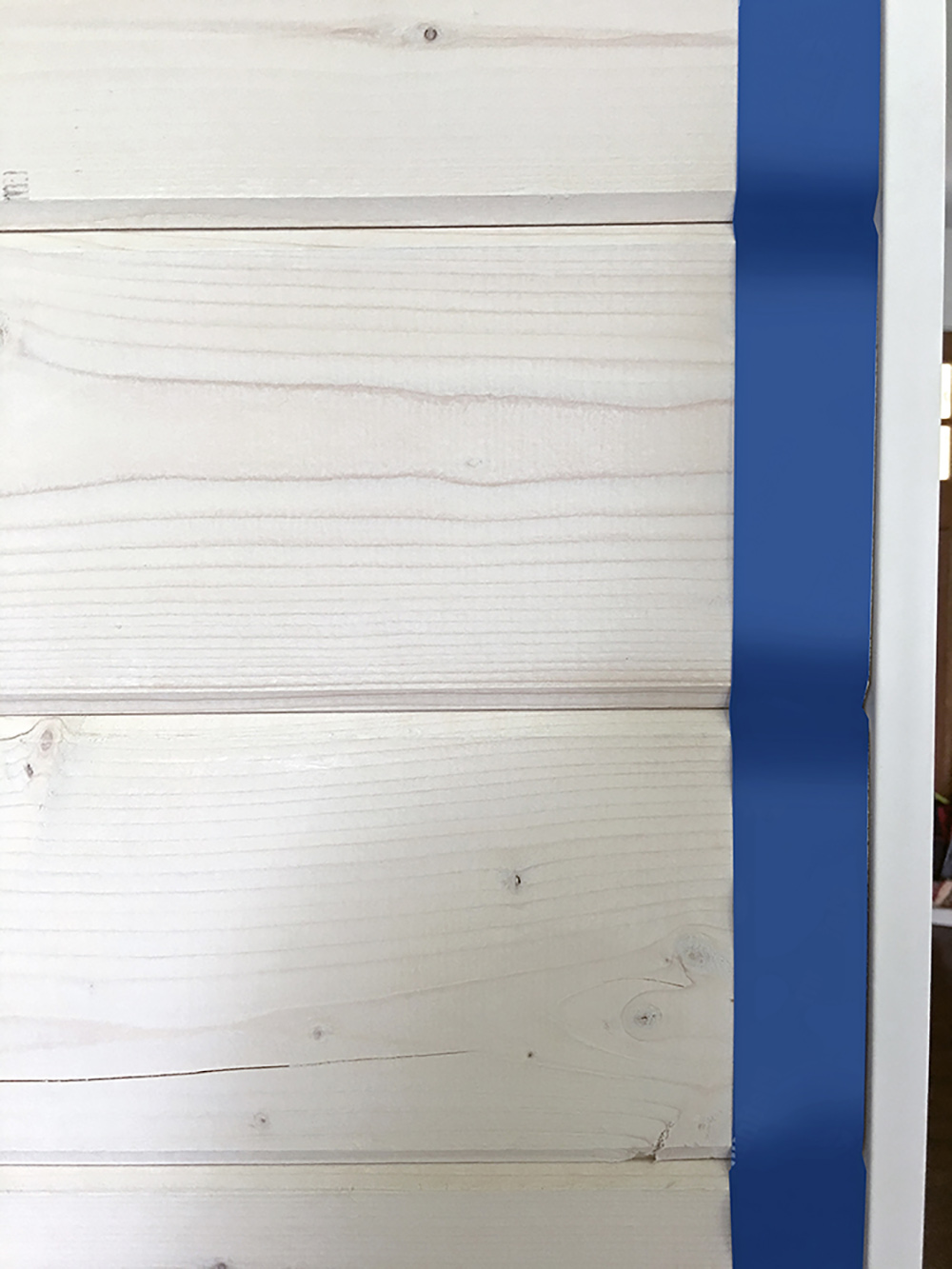 A piece of painter's tape between beachwood boards and a piece of trim. A piece of painter's tape between beachwood boards and a piece of trim.
