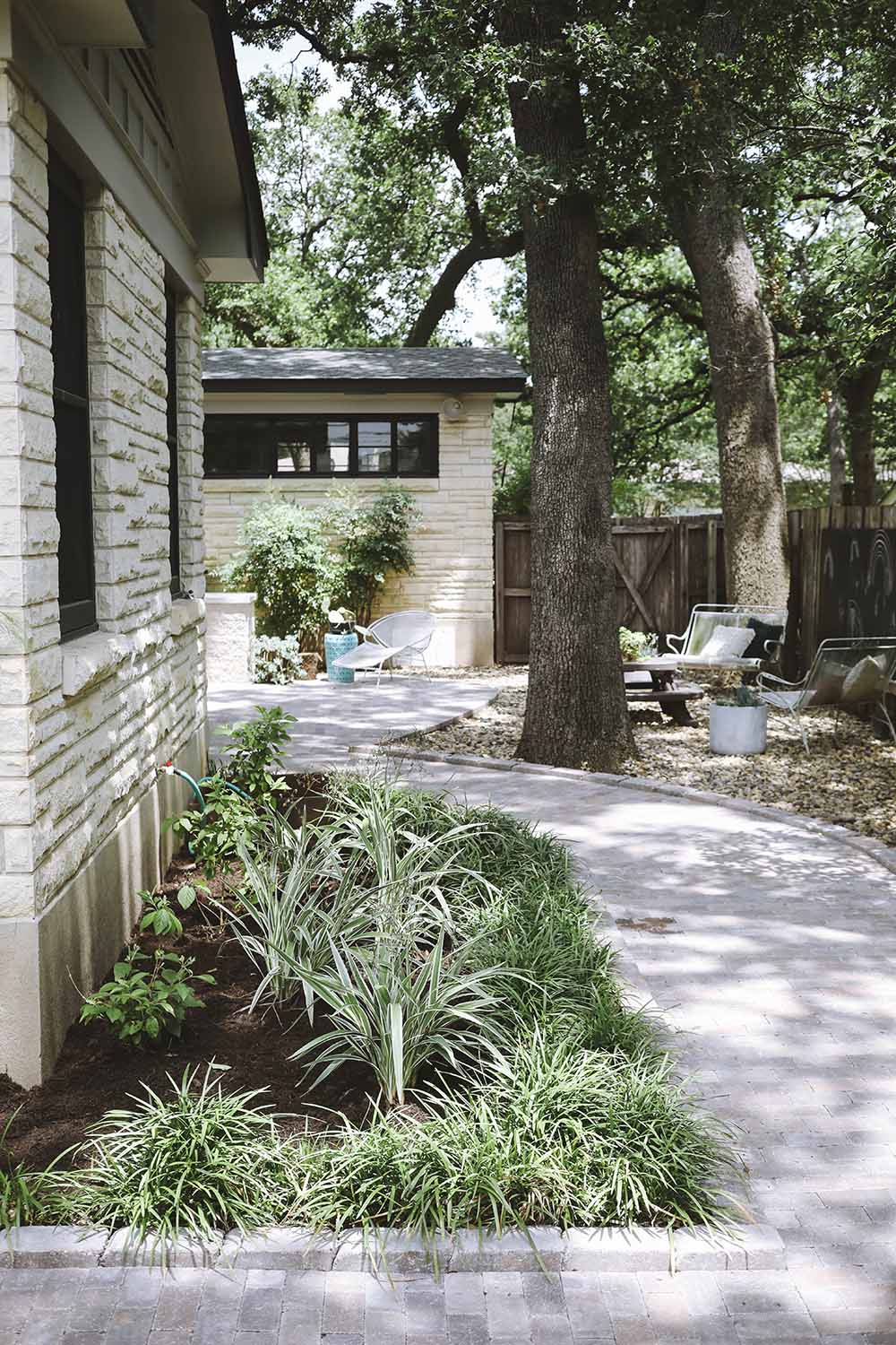 A path of pavers leading to a backyard on the side of a home.