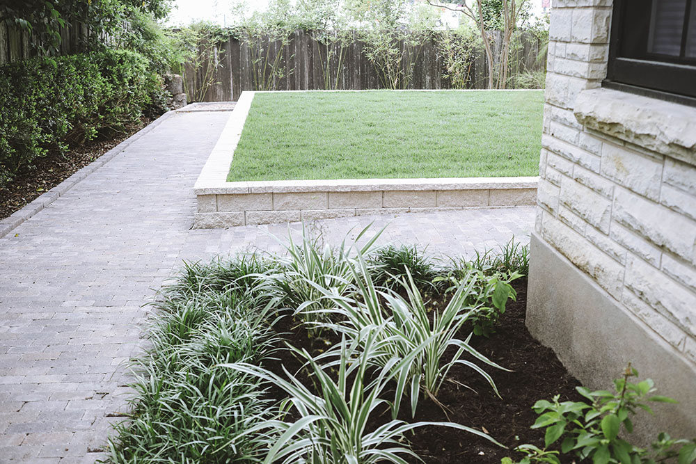A paved pathway leading to a landscaped backyard.
