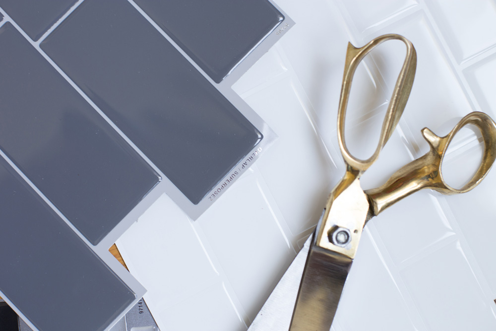 A pair of scissors laid next to a sheet of Smart Tiles.