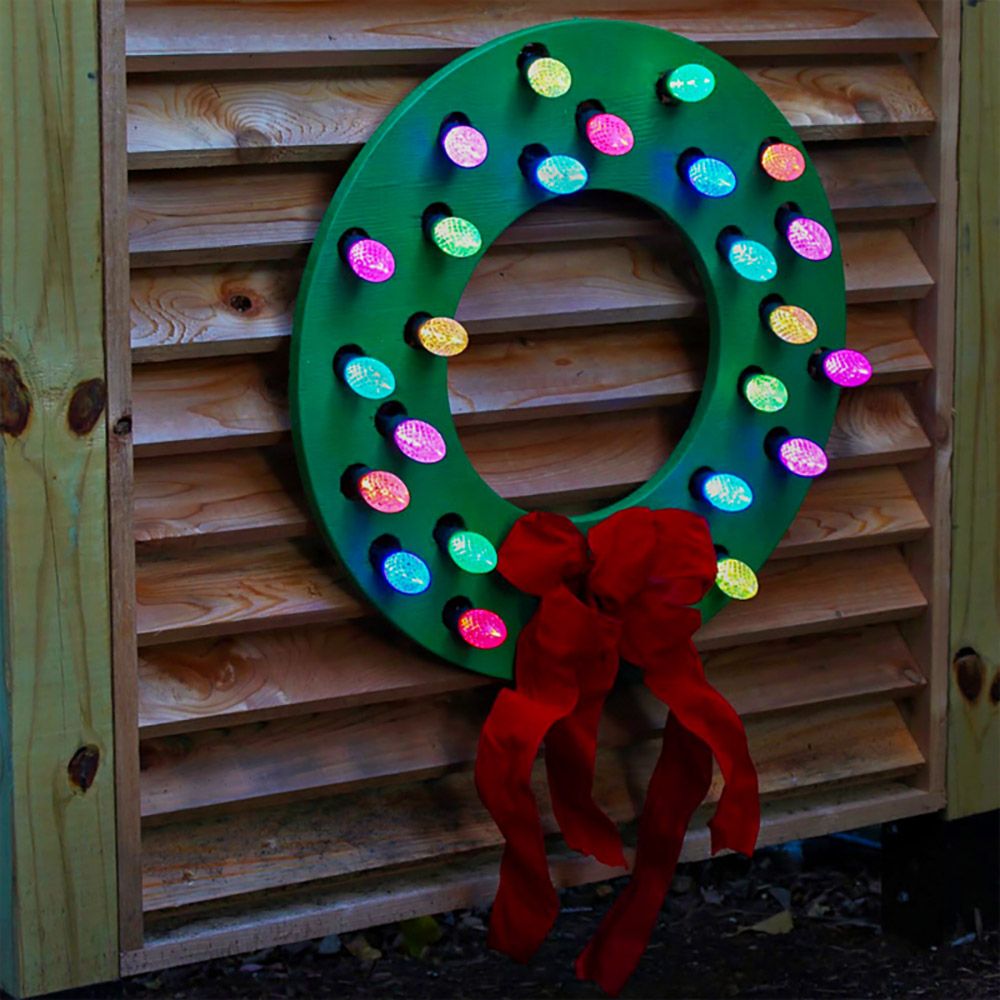 A DIY wood wreath with a red bow and multi-colored lights.