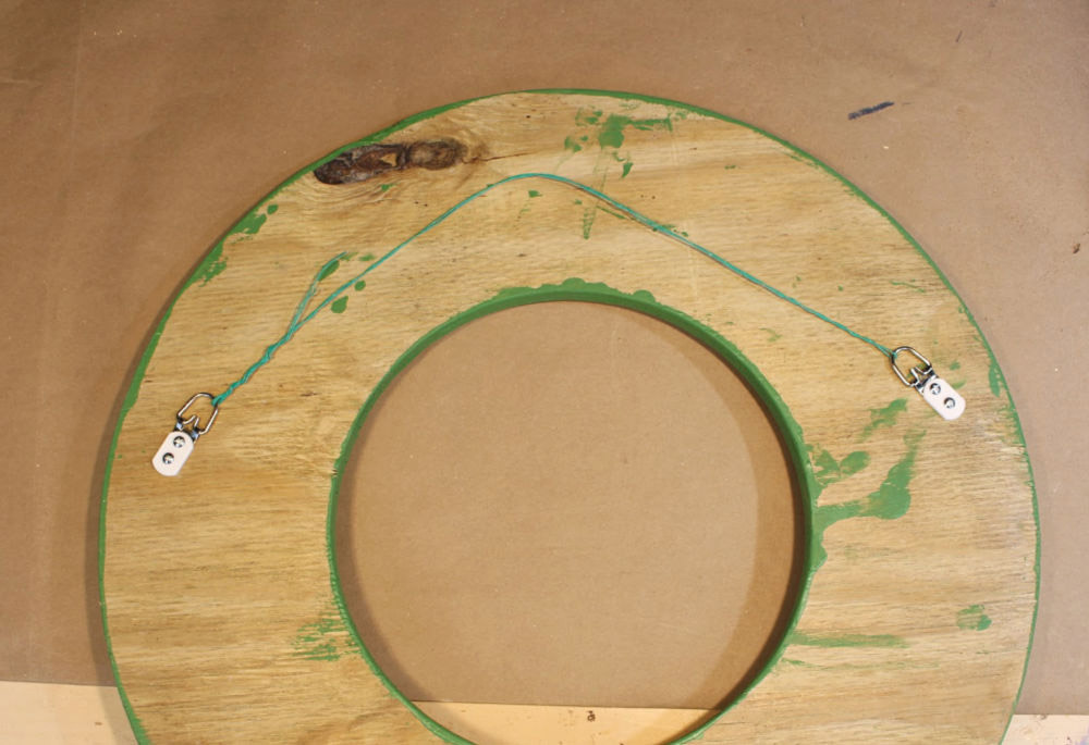 A hanging wire on the back of a wooden circle with a cut out center.