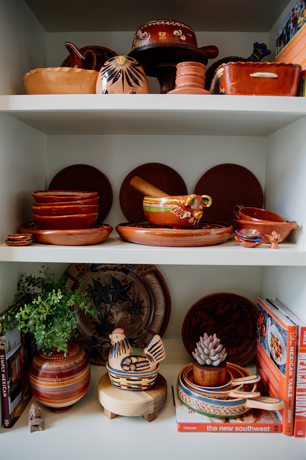 Several bookshelves decorated with Mexican pottery.