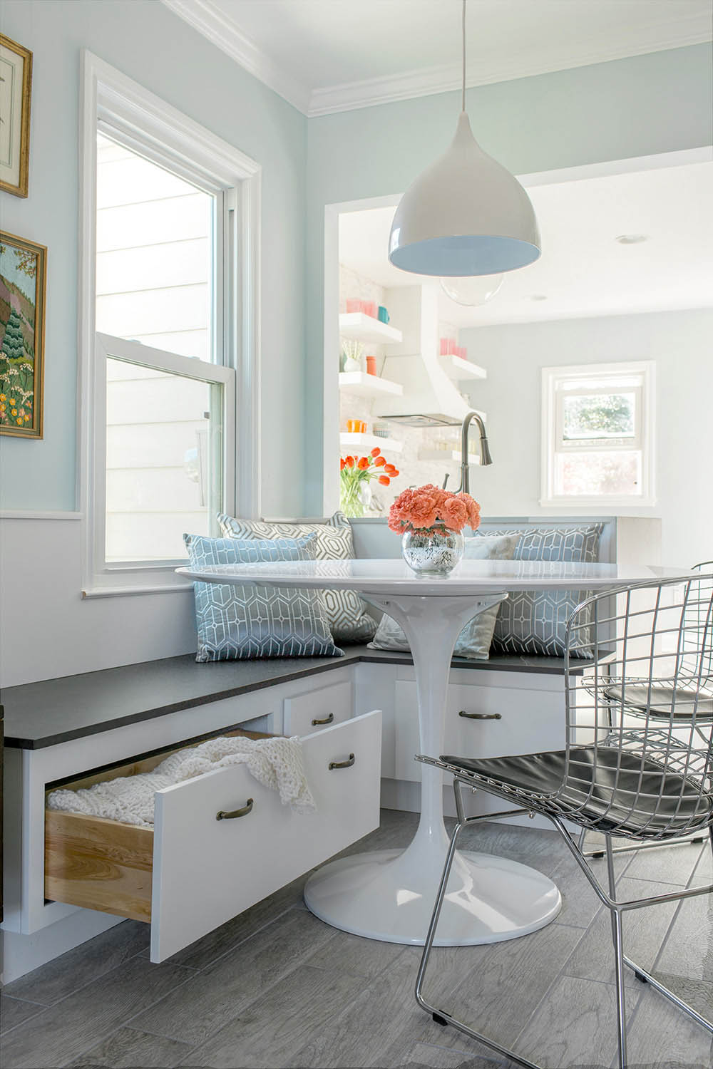 White drawers below a bench open to show additional storage space and a white table. 