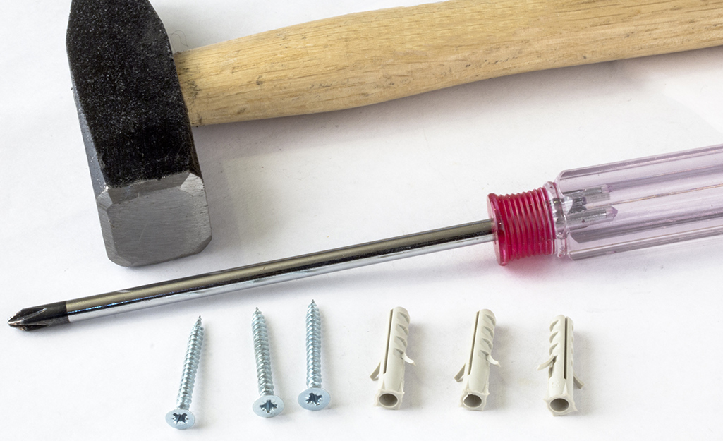 A hammer and screwdriver with screws and drywall anchors. A hammer and screwdriver with screws and drywall anchors.