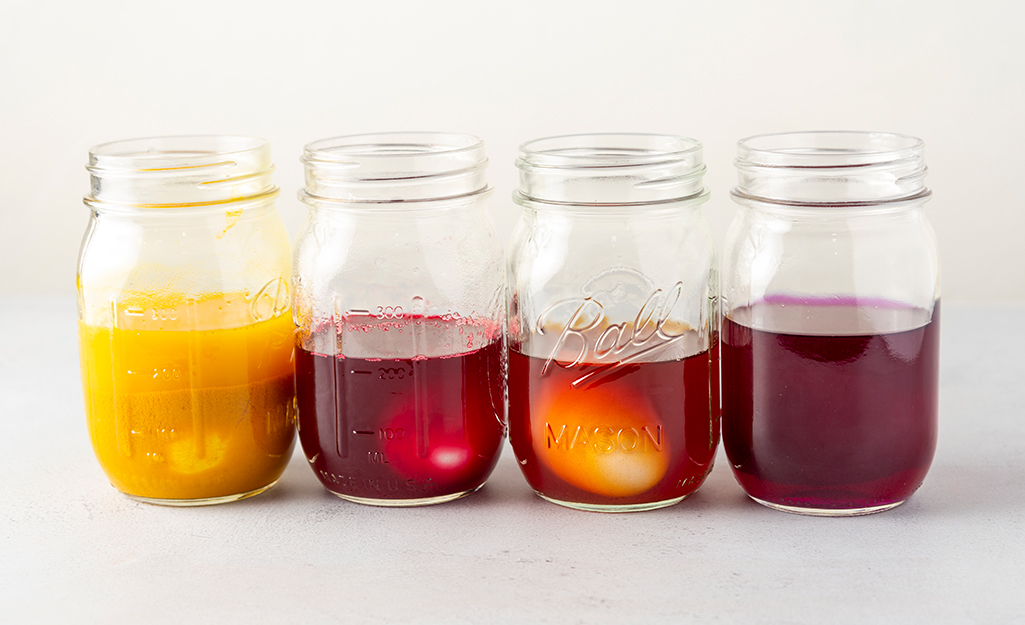 Four canning jars with colored water and eggs in them. Four canning jars with colored water and eggs in them.